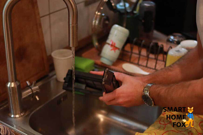 Der Schmutzbehälter des Roomba j7 wird unter fließendem Wasser gereinigt